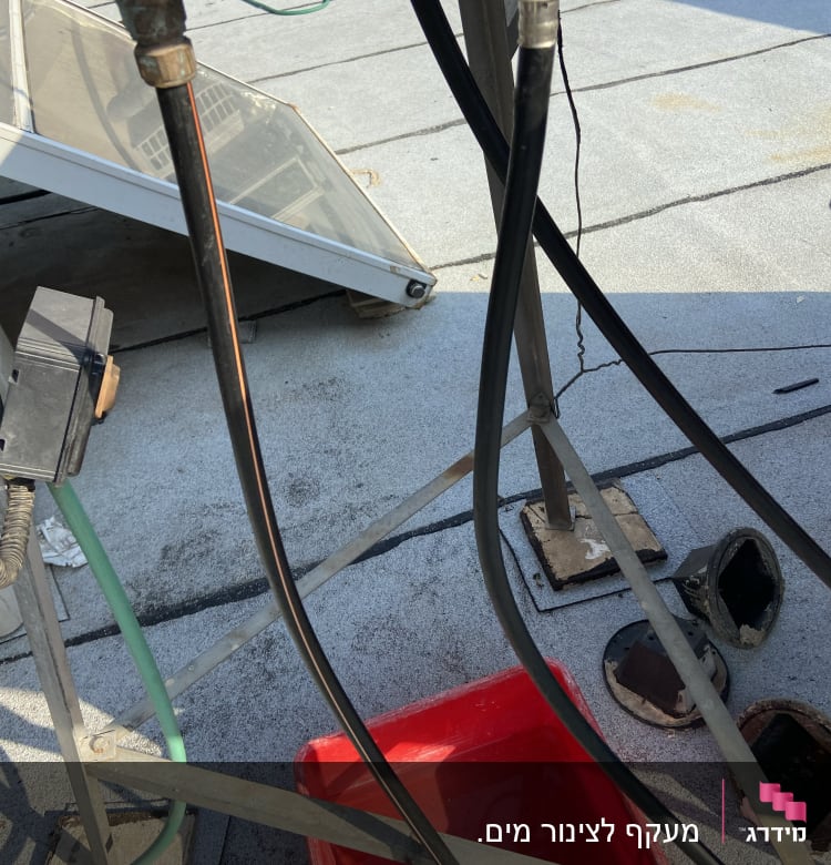 צינורות מים מחוברים לברזים מעל דלי אדום